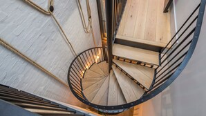 A spiral staircase with wooden steps and metal railings, surrounded by rope and a white brick wall. - The Insta Playhouse - Covent Garden - by Frankie Says (London)