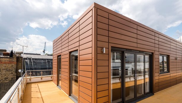 Un edificio moderno con grandes puertas de vidrio y una terraza de madera.