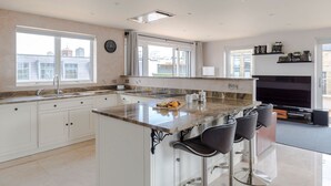 Una cocina moderna con una isla central, taburetes de bar, un ventanal grande y una chimenea.