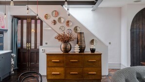 Un interior moderno con un armario de madera, platos decorativos y una escalera.