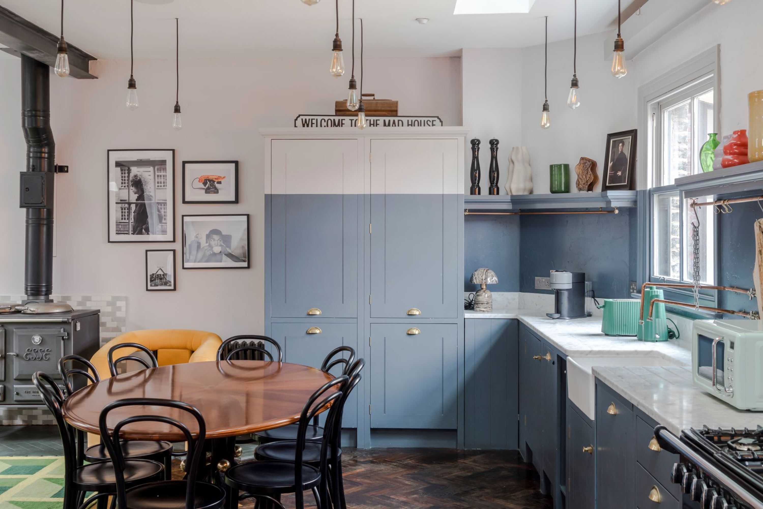 A kitchen with a wooden dining table, blue cabinets, and a stove.
