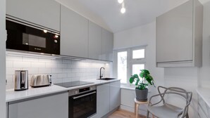 A modern kitchen with white cabinets, a Bosch microwave, a toaster, and a sink. - Stairway To Heaven - Fitzrovia - by Frankie Says (London)