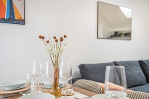 A dining table set with wine glasses, plates, and a vase with dried flowers. - The Cutesy - Fitzrovia - by Frankie Says (London)