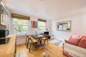 Une cuisine moderne avec une table à manger, des chaises, un téléviseur et une grande fenêtre.