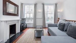 Un salon moderne avec une cheminée, un canapé, une table basse et une grande fenêtre avec des rideaux.