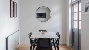 A dining area with a marble table, black chairs, a round mirror, and framed artwork on the wall. - London s Calling - Farringdon - by Frankie Says (London)