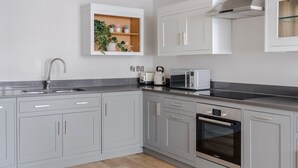 A modern kitchen with grey cabinets, a Bosch oven, a microwave, and a built-in plant shelf. - London s Calling - Farringdon - by Frankie Says (London)