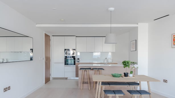 A modern kitchen with white cabinets, a central island, and bar stools. - Zen Sanctuary - Soho - by Frankie Says (London)