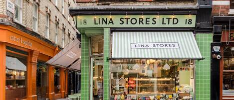 A storefront with a green awning and a sign reading "LINA STORES LTD 18".