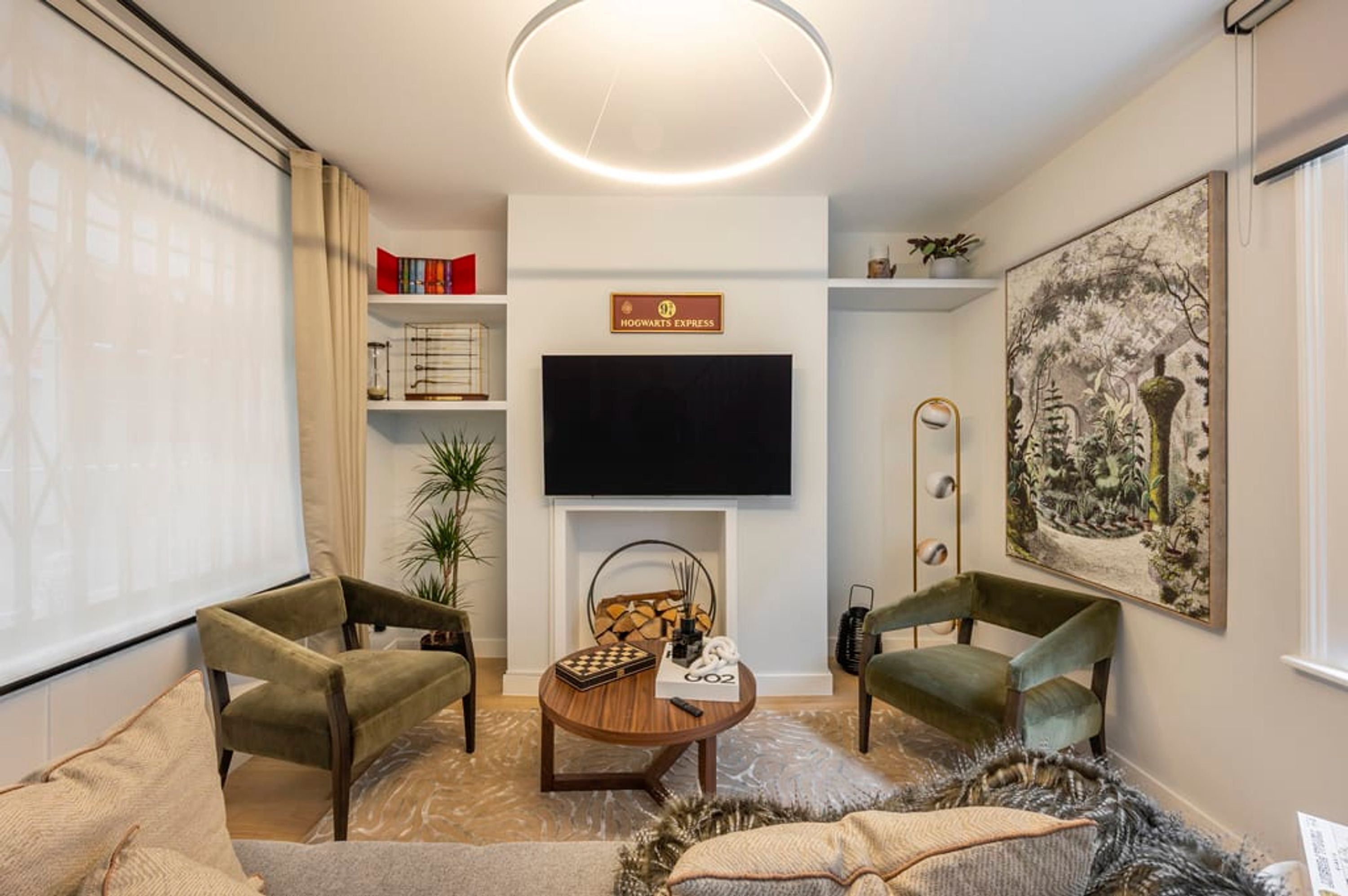 A living room with a flat-screen TV, a fireplace, and a sign reading "Hogwarts Express".