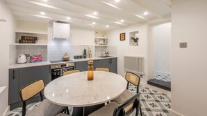 A modern kitchen with a round dining table, grey cabinets, and a white ceiling with recessed lighting. - Pottter s Perch - Covent Garden - by Frankie Says (London)