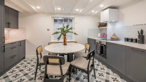 A modern kitchen with a round dining table, grey cabinets, and a patterned floor. - Pottter s Perch - Covent Garden - by Frankie Says (London)