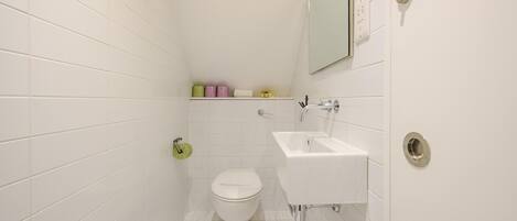 A small, white bathroom with a toilet, sink, and mirror.