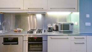 Et moderne køkken med rustfrie hvidevarer, herunder en mikrobølgeovn, brødrister og ovn.