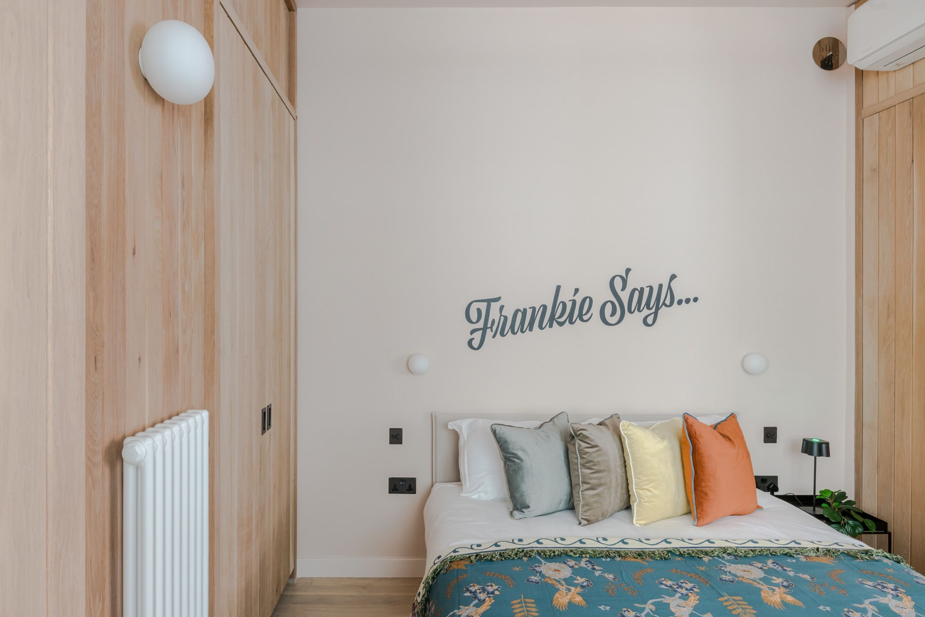 Une chambre à coucher avec un lit, une lampe fixée au mur et un radiateur.