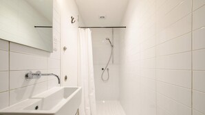 A modern bathroom with a white bathtub, a shower with a handheld showerhead, and a glass-enclosed shower stall.