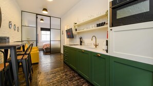 A modern kitchen with green cabinets, a white countertop, and a built-in oven.