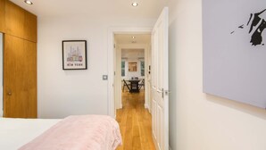 A bedroom with a bed, wooden wardrobe, and a framed picture of New York on the wall. - The Play Pen - Holborn - by Frankie Says (London)