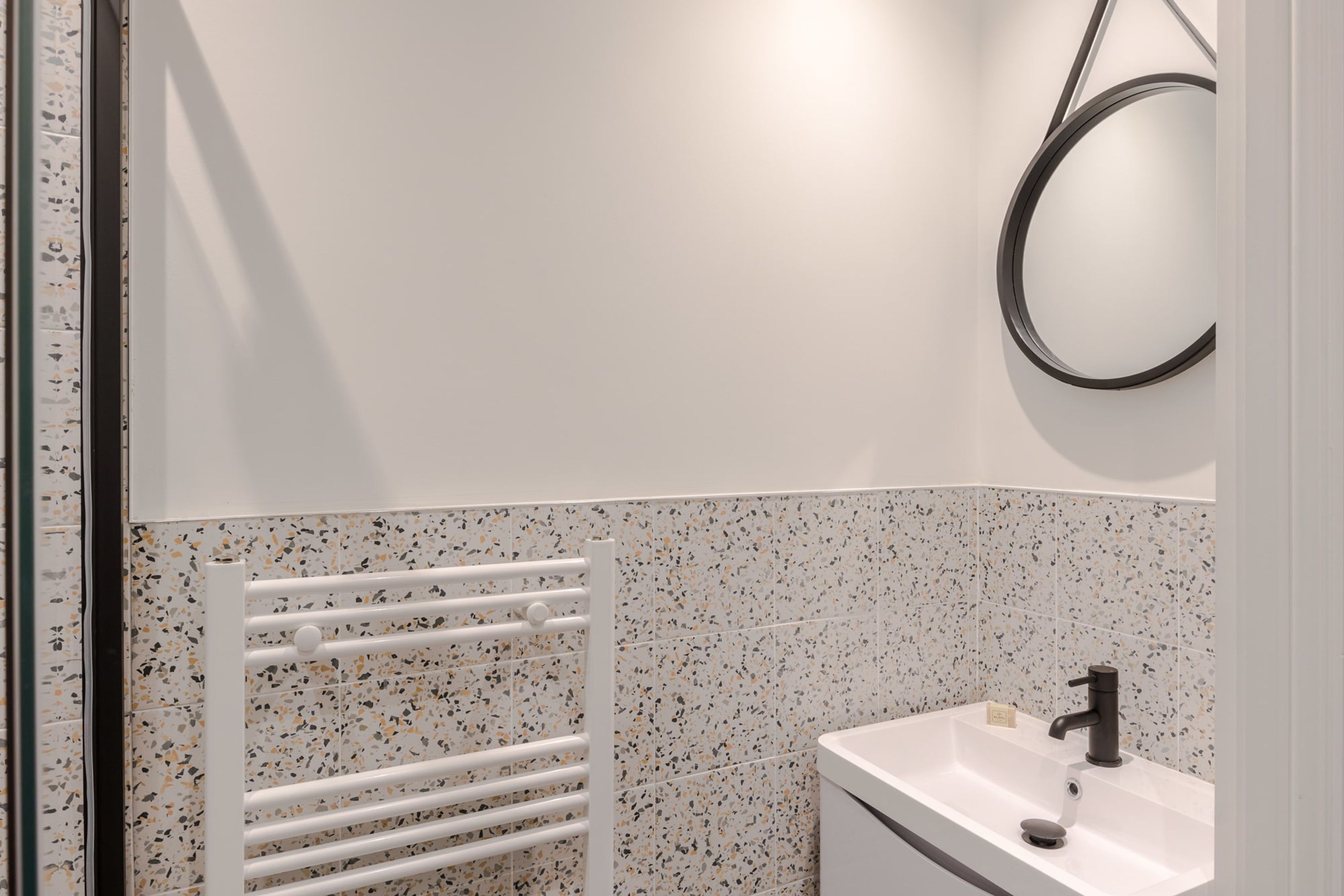 A bathroom with a white sink, a black faucet, and a white towel rack.