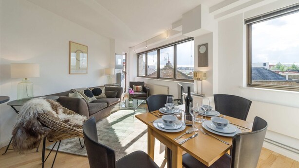 Ein modernes Wohnzimmer mit Essbereich, großen Fenstern und Blick auf die Stadt.