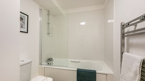 A bathroom with a glass-enclosed shower, a white bathtub, and a toilet.