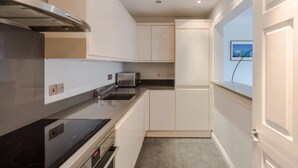 Una cocina moderna con armarios blancos, un microondas integrado y una campana extractora de acero inoxidable.