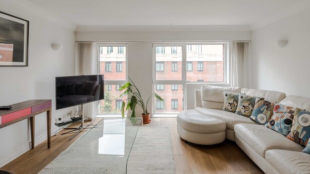 Una sala de estar moderna con un gran ventanal, un televisor de pantalla plana, un sofá y una planta en maceta.