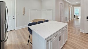 A modern kitchen with a marble island, wooden flooring, and white cabinetry. - Seaside Villa - Gulf Breeze with an Ocean View! (Long Beach)