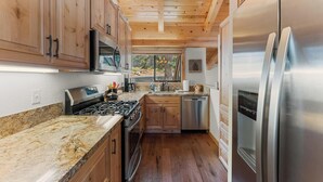 Une cuisine moderne avec des meubles en bois, des appareils en acier inoxydable et un plan de travail en granit.