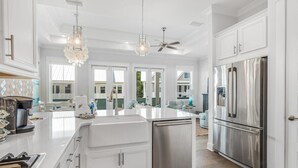 A spacious kitchen with white cabinetry, a stainless steel refrigerator, and a central island. - 🔆 Golf Cart | Bikes | The Big Chill | Resort Pools ​​​​​​ (Inlet Beach)