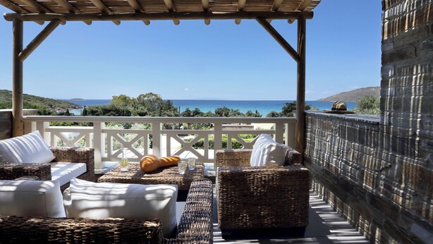 A covered outdoor seating area with wicker furniture and a view of the sea. - Aithra Andros (Andros)
