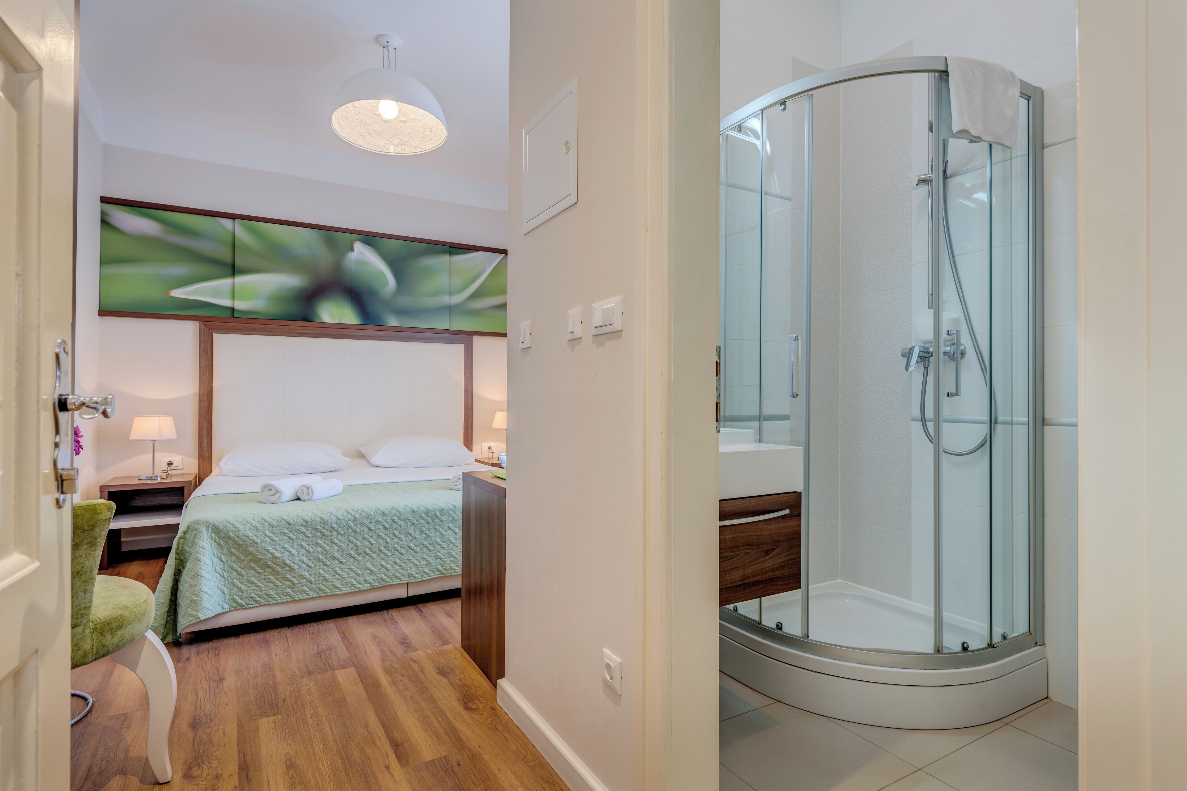 Una habitación de hotel con cama, ducha y una silla.