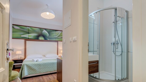 A hotel room with a bed, a shower, and a chair. - Bastion Luxury Rooms (Split)