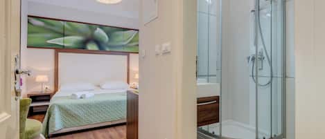 Una habitación de hotel con cama, ducha y una silla.