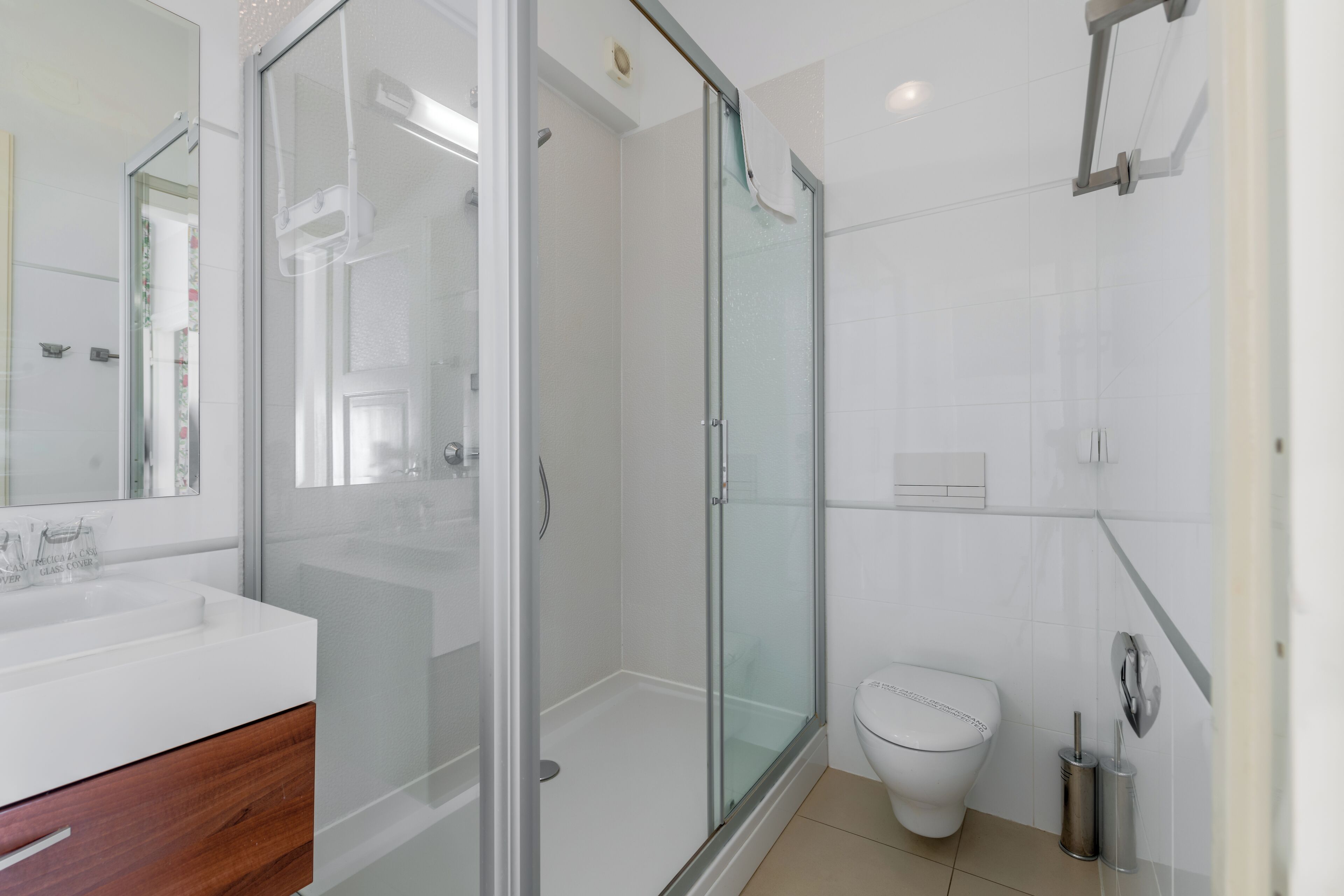 Un baño moderno con cabina de ducha de vidrio, un lavamanos blanco y un inodoro.