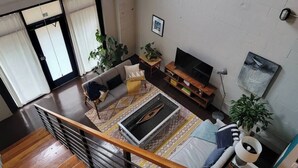 A modern living room with a sofa, TV, and plants. - Amazing Loft in Historic Springfield (Jacksonville)