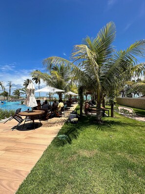 Un espace aménagé au bord de la piscine, avec des chaises longues, des parasols et une pelouse.