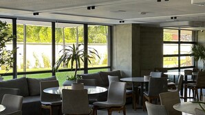 Un amplio espacio interior con diversas opciones de asientos, ventanas grandes que ofrecen vistas a la vegetación y un diseño de techo moderno.