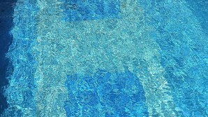 A clear view of a swimming pool with visible water ripples and reflections.