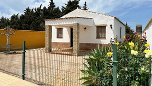 A small white building with a tiled roof and a fenced patio area. - Casa Antonio III 113 (Conil de la Frontera)