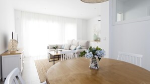 A modern living room with a round wooden dining table, white furniture, and a vase of flowers. - Selecta I 32321 in Conil de la Frontera (Conil de la Frontera)