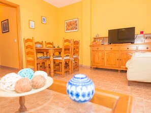 Cozy living room with a dining table for four, a flat-screen TV, and a comfortable sofa.