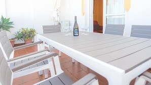 Eine Terrasse mit Tisch und Stühlen, einer Weinflasche und Topfpflanzen.