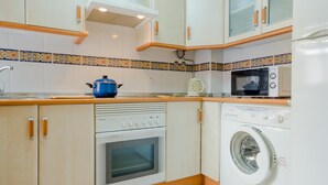 Une cuisine compacte équipée d’une cuisinière, d’un four, d’un four à micro-ondes et d’un lave-linge.