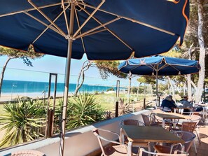 An outdoor seating area with tables and chairs, umbrellas, and a view of the beach and ocean. - Las Torres 419 in Conil de la Frontera (Conil de la Frontera)