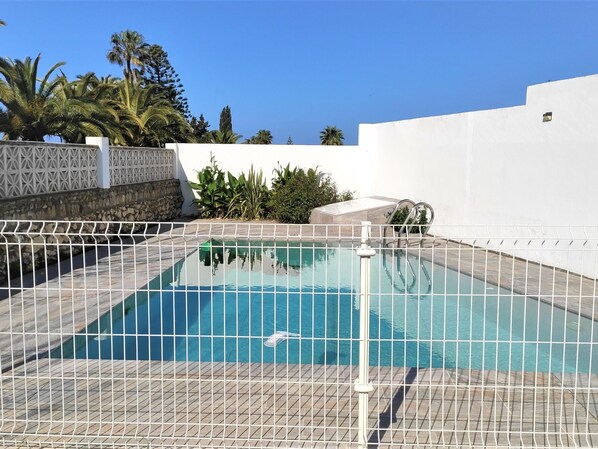 A rectangular swimming pool with a tiled deck, surrounded by a white fence. - Calma Holiday Home 22606 (Conil de la Frontera)