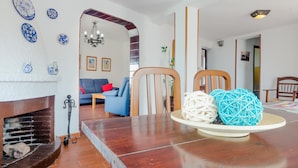 Ein Wohnzimmer mit Kamin, blauen Sofas, einem Esstisch mit dekorativen Kugeln und einem Spiegel.