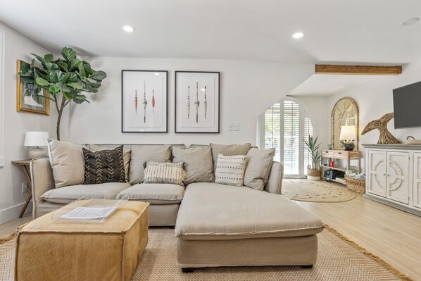 A modern living room with a sectional sofa, a wooden coffee table, and a large plant.