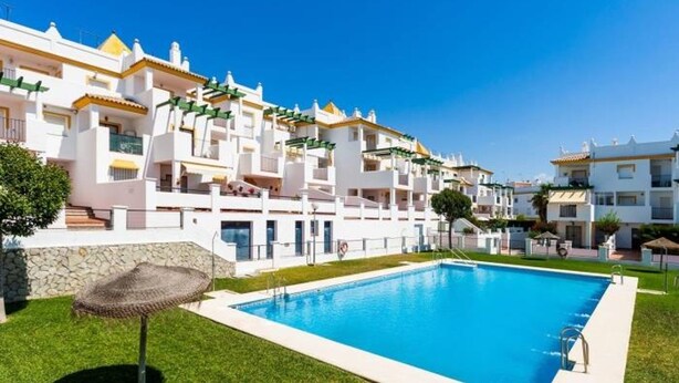 A modern hotel with a swimming pool, white buildings, and a well-maintained lawn. - Apartamento Canela 2536 (Conil de la Frontera)