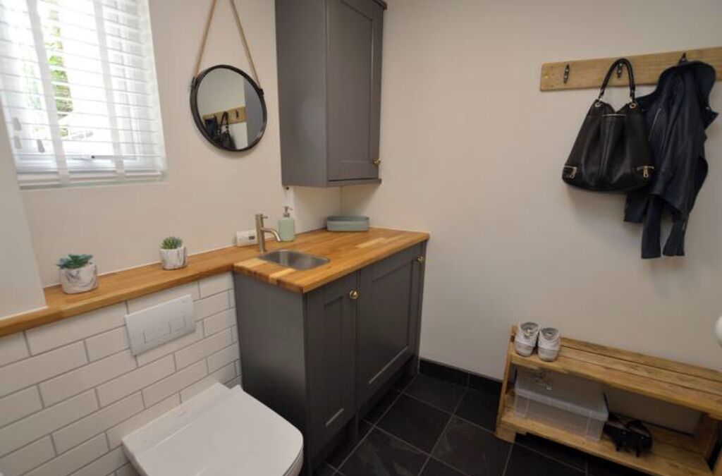 A compact kitchen with a wooden countertop, a sink, and a small wooden shelf.